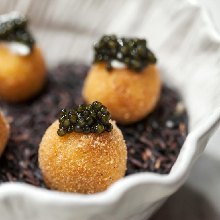 Blurry background of black caviar roe placed on food in a white bowl in the kitchen